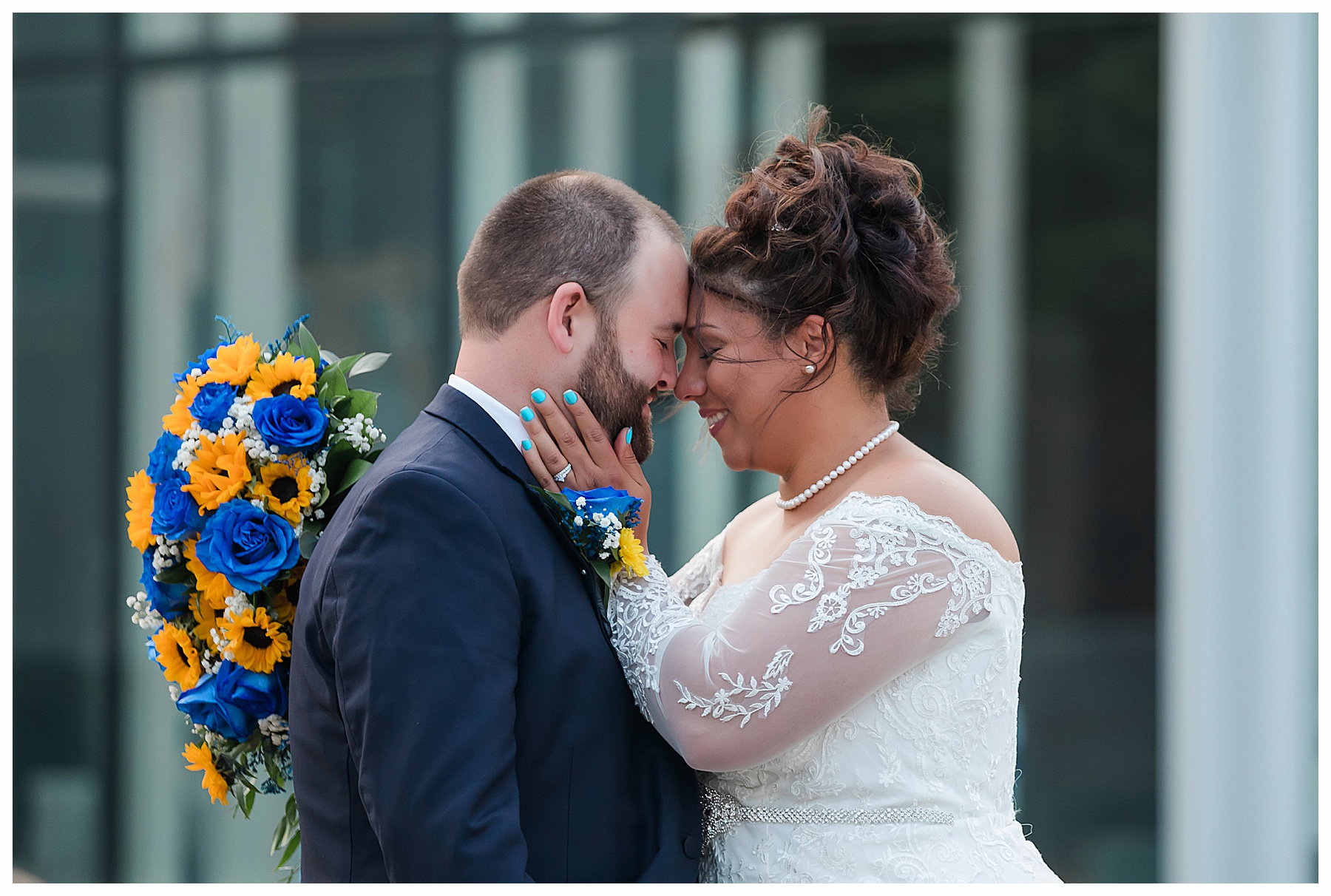 Bride holds blue and yellow bouquet while touching grooms face.  Bismarck Heritage Center